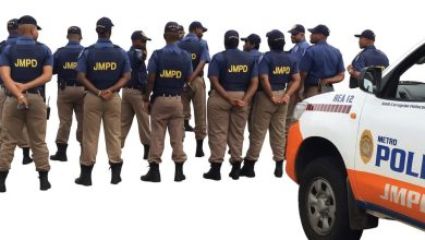 Police officers stand beside a police truck, promoting the JMPD Training Program for aspiring Metropolitan Police Officers.