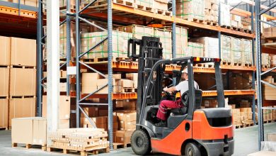 A forklift truck in a warehouse surrounded by stacked boxes and shelves, indicating job openings for forklift drivers.