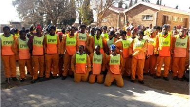 A group of men wearing orange and yellow vests, part of the Metrobus EPWP General Worker Program, standing together.