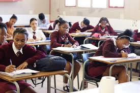 A classroom scene showing students at desks, concentrating on their exams.