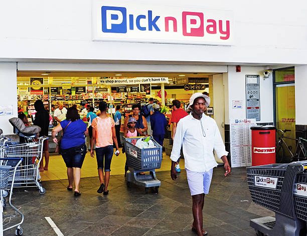 A man strides past a Pick n Pay store, highlighting learnership opportunities in wholesale and retail for 2026.