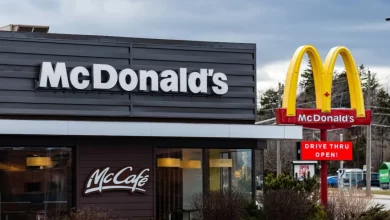 A woman in a blue uniform is positioned at a McDonald's kiosk, advertising job openings for 2025.